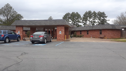 A view of a brick building with a parking area under cloudy skies.