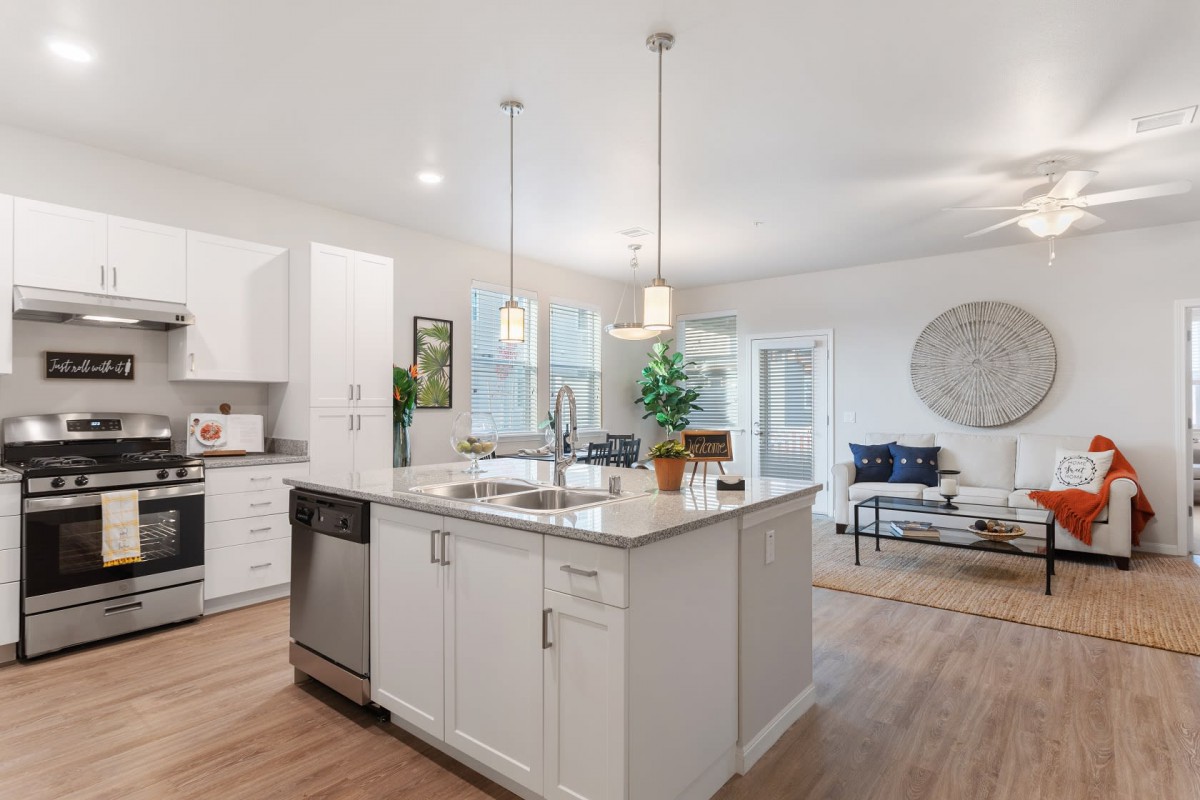 A modern kitchen with a central island and pendant lighting, featuring white cabinets and an open layout.