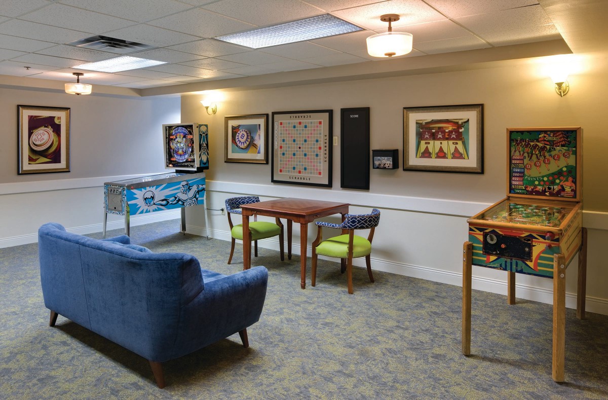 An inviting game room featuring pinball machines, a table with chairs, and various artworks on the walls.