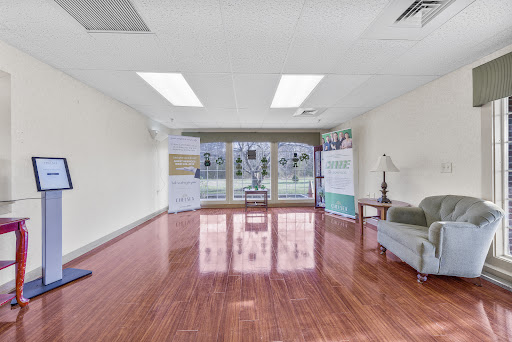 A bright and spacious empty office room featuring wooden flooring and large windows.