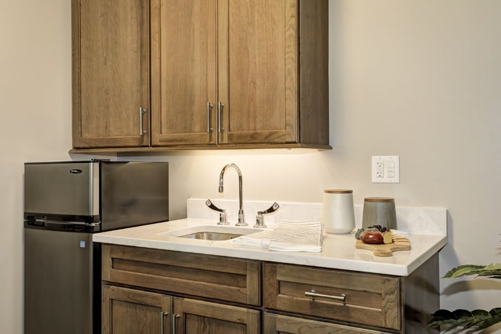A modern kitchen corner featuring wooden cabinets, a sink with a sleek faucet, and small appliances on the countertop.