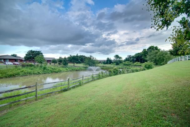 A serene landscape featuring a river under a partly cloudy sky, surrounded by lush greenery.