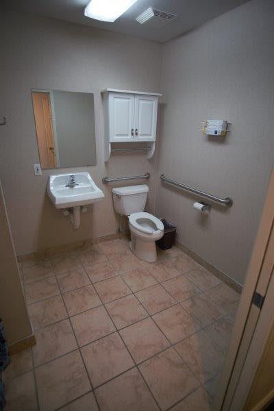 A clean and accessible bathroom with a sink, toilet, and grab bars.