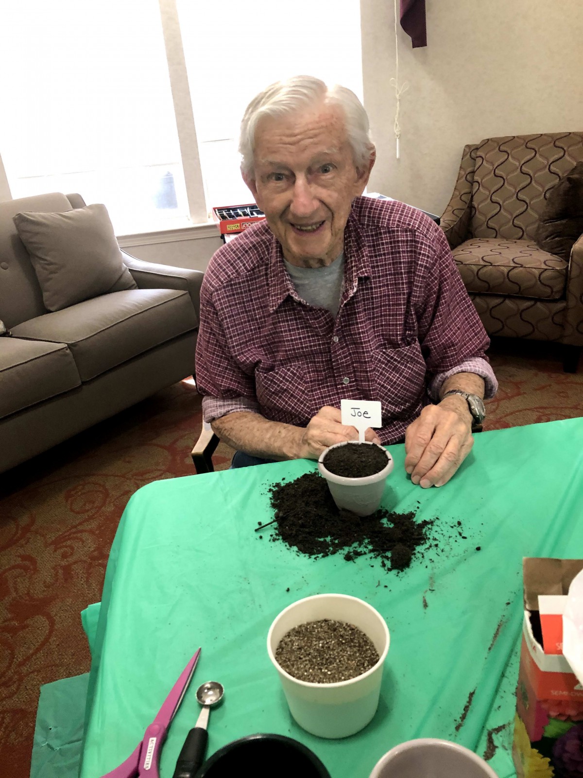An elderly person enjoying an indoor gardening activity with soil and a small pot.