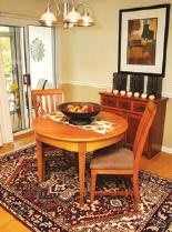 A cozy dining area with a round wooden table and two chairs, set on a patterned rug.