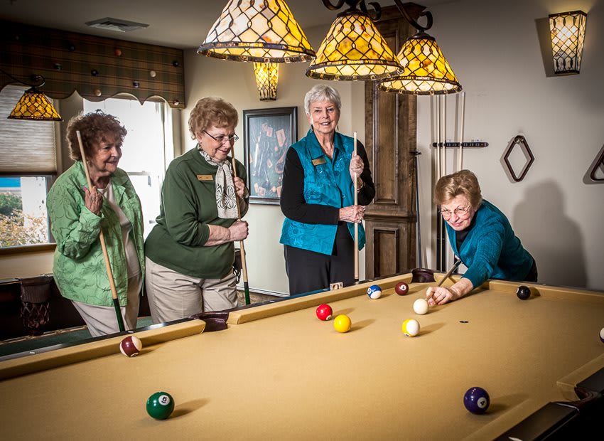 A group of seniors enjoying a game of billiards indoors.