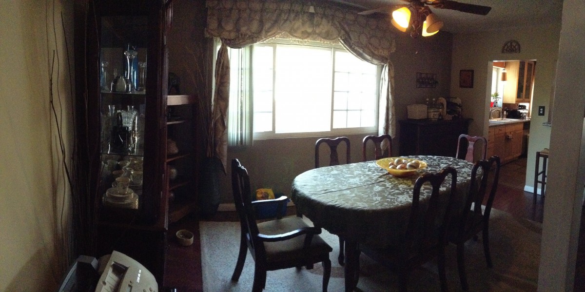 A dining room with a table and chairs near a window adorned with curtains.