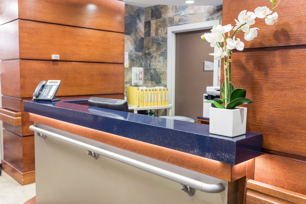 A modern reception desk in an office lobby with decorative flowers.