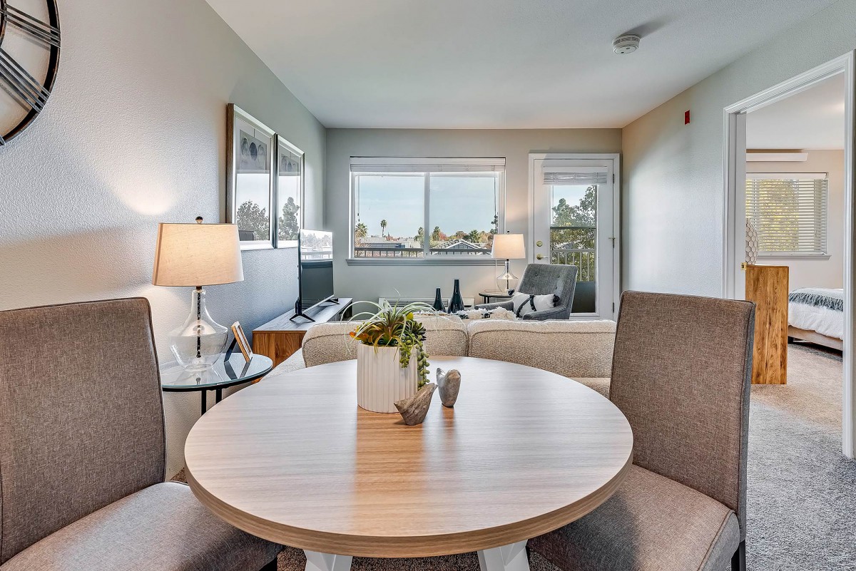 A modern apartment living room with a dining area, featuring cozy furniture and ample natural light.