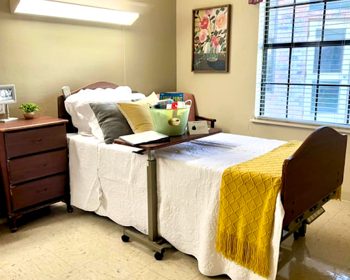 A cozy and well-arranged bedroom featuring a hospital bed with comfortable bedding and personal touches.
