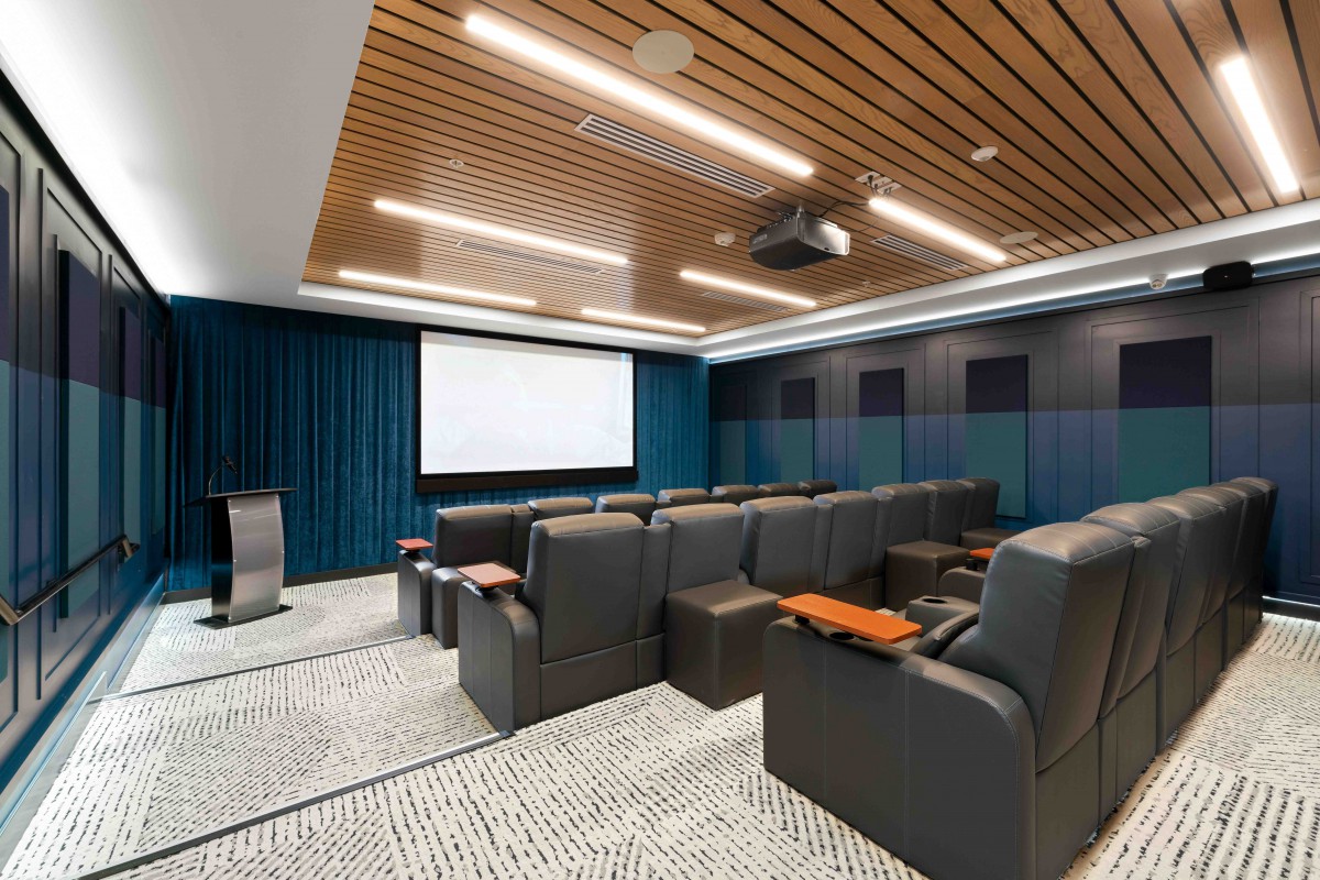 A modern home theater room featuring comfortable seating and a large screen.