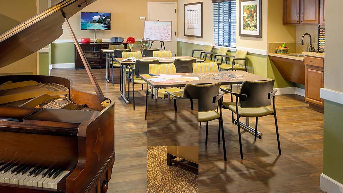 A well-organized classroom with tables, chairs, and a whiteboard, featuring a piano in the foreground.