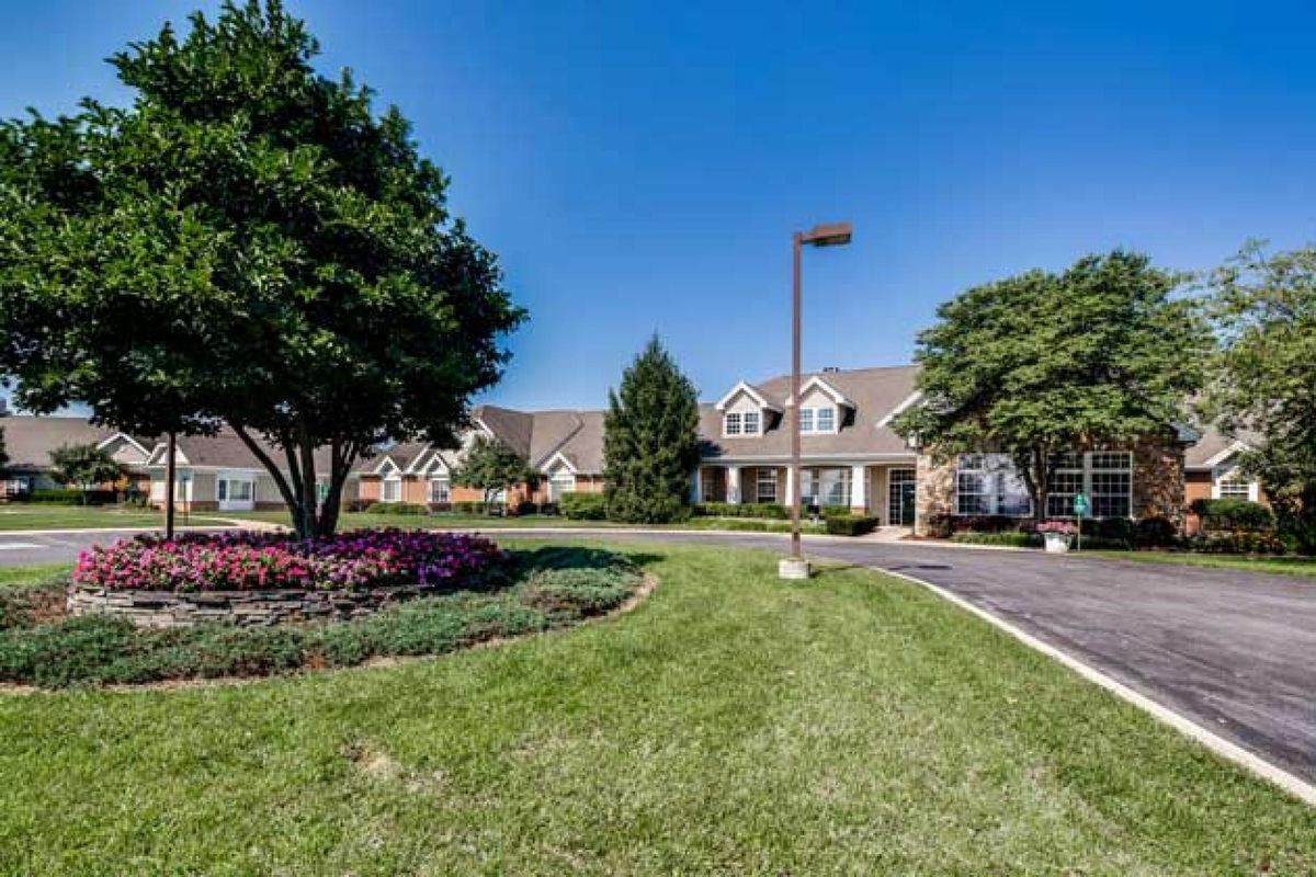 A well-maintained building surrounded by a lush landscape with trees and colorful flower beds.