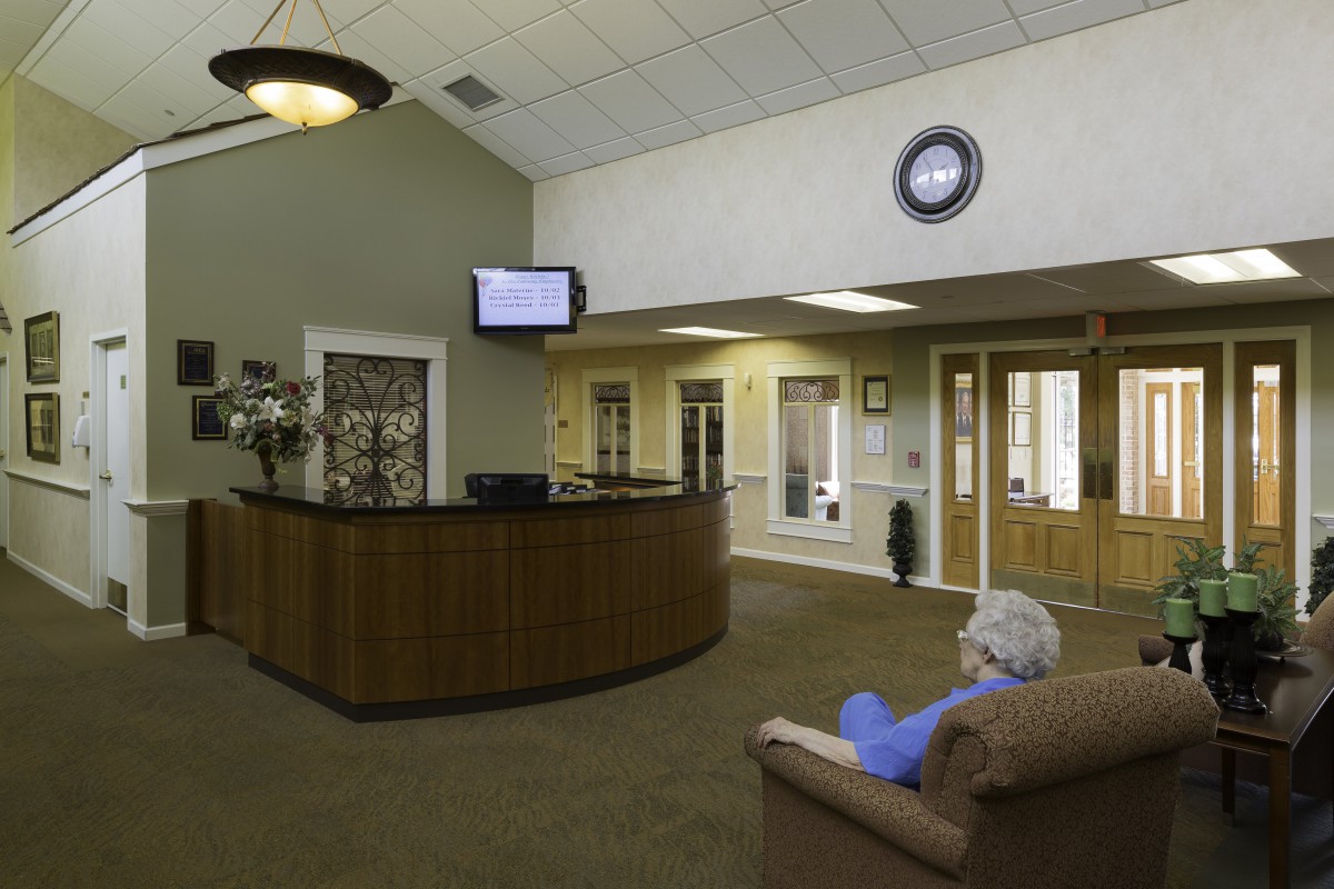 A quiet waiting room with a reception desk, seating area, and a television mounted on the wall.