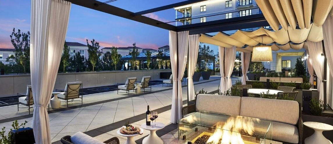 A luxurious outdoor patio with a fire pit, cozy seating, and wine for a relaxing evening ambiance.