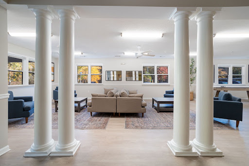 A modern living room featuring elegant columns, comfortable seating, and vibrant artwork.