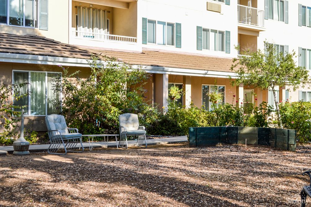 A well-maintained garden area with outdoor seating in front of a residential building.
