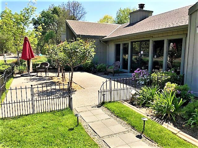 A cozy house with a well-maintained garden and patio area, perfect for outdoor relaxation on a sunny day.