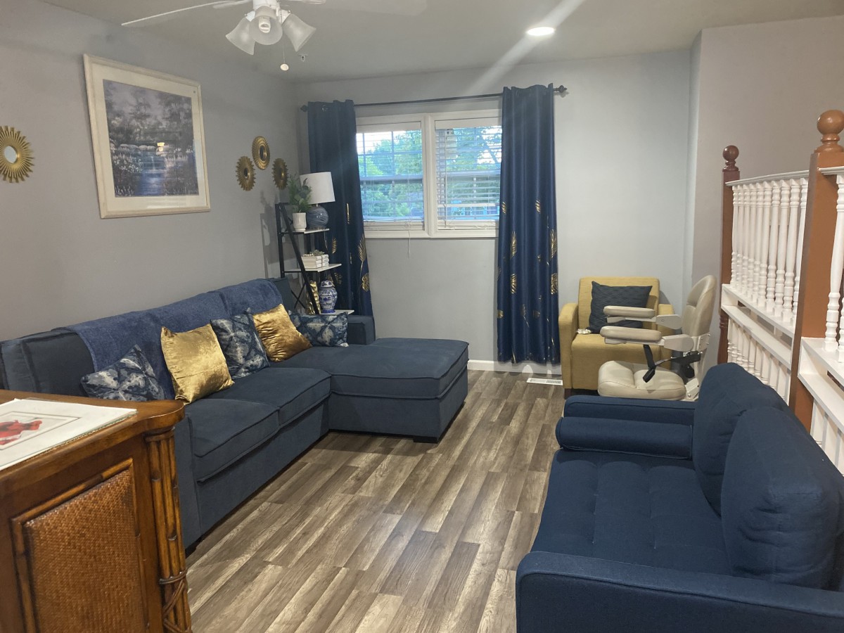 A cozy living room with blue furniture and wood flooring.