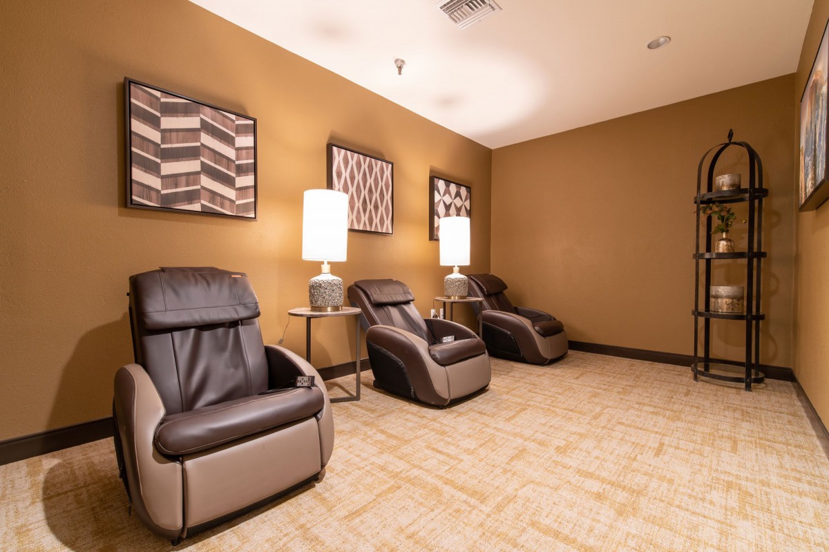 A tranquil relaxation room featuring comfortable massage chairs and warm lighting.