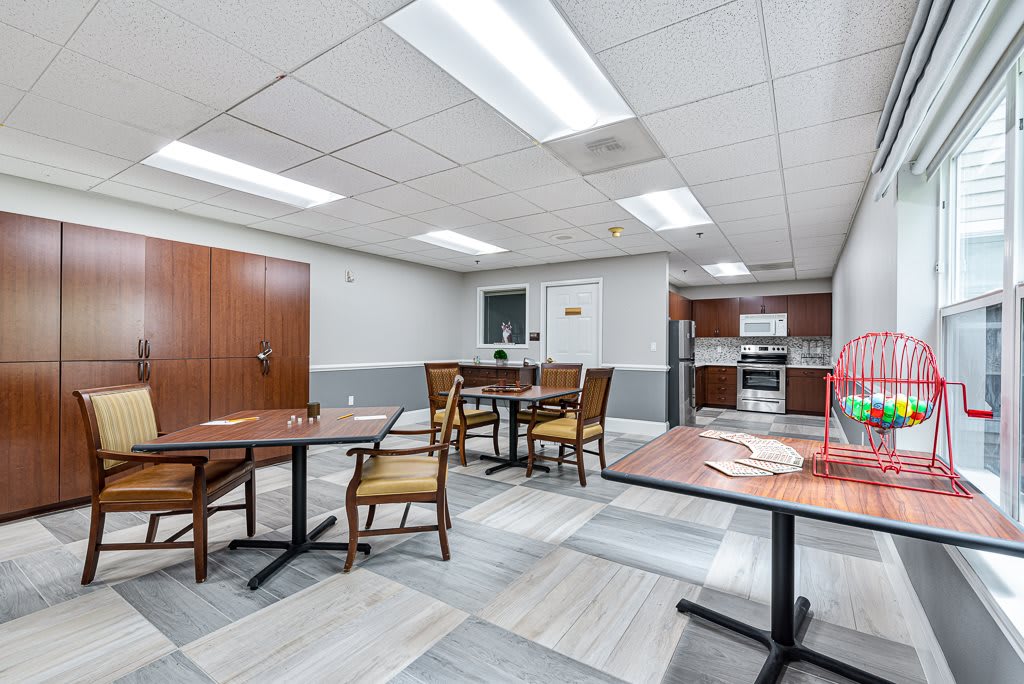 A communal kitchen area with tables and chairs, featuring a modern design and equipped with appliances.