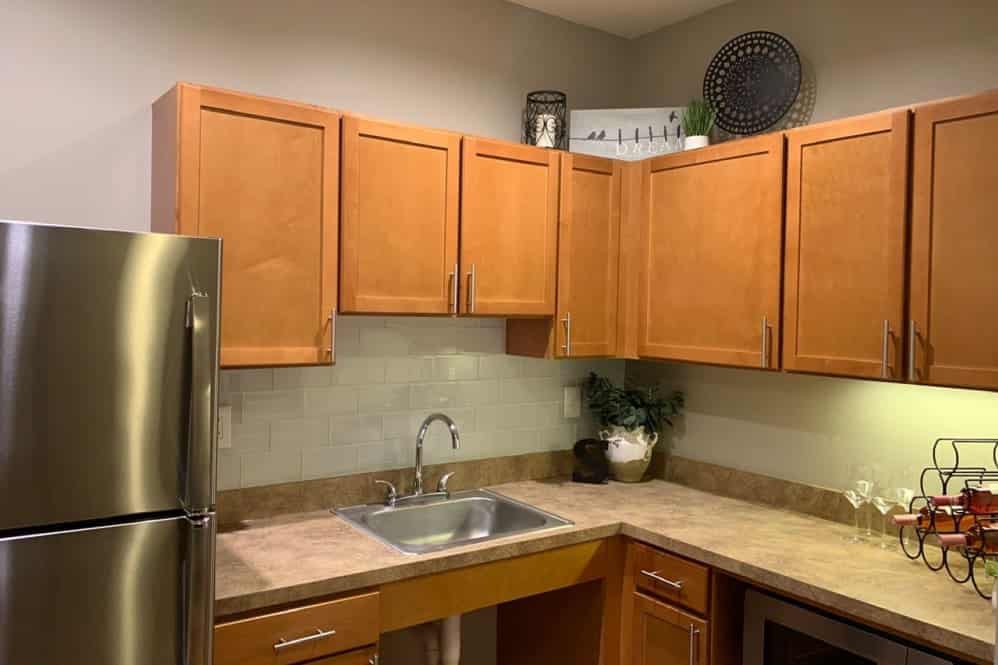 A modern kitchen featuring wooden cabinets and a sleek countertop with a stainless steel sink.