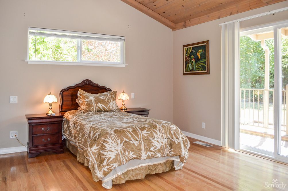 A cozy bedroom with a single bed, wooden flooring, and soft lighting from bedside lamps.