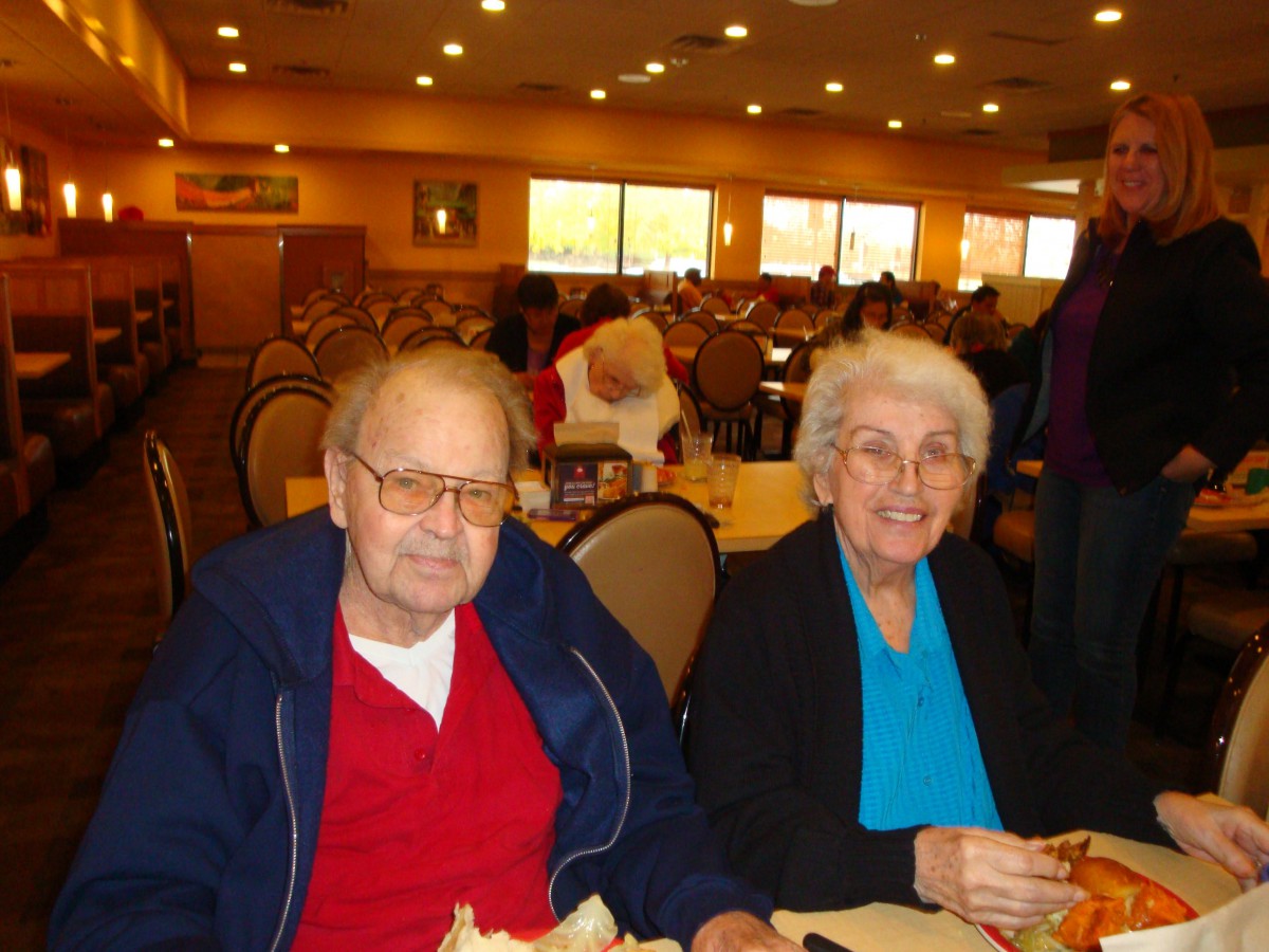 An elderly couple smiling while dining in a restaurant.
