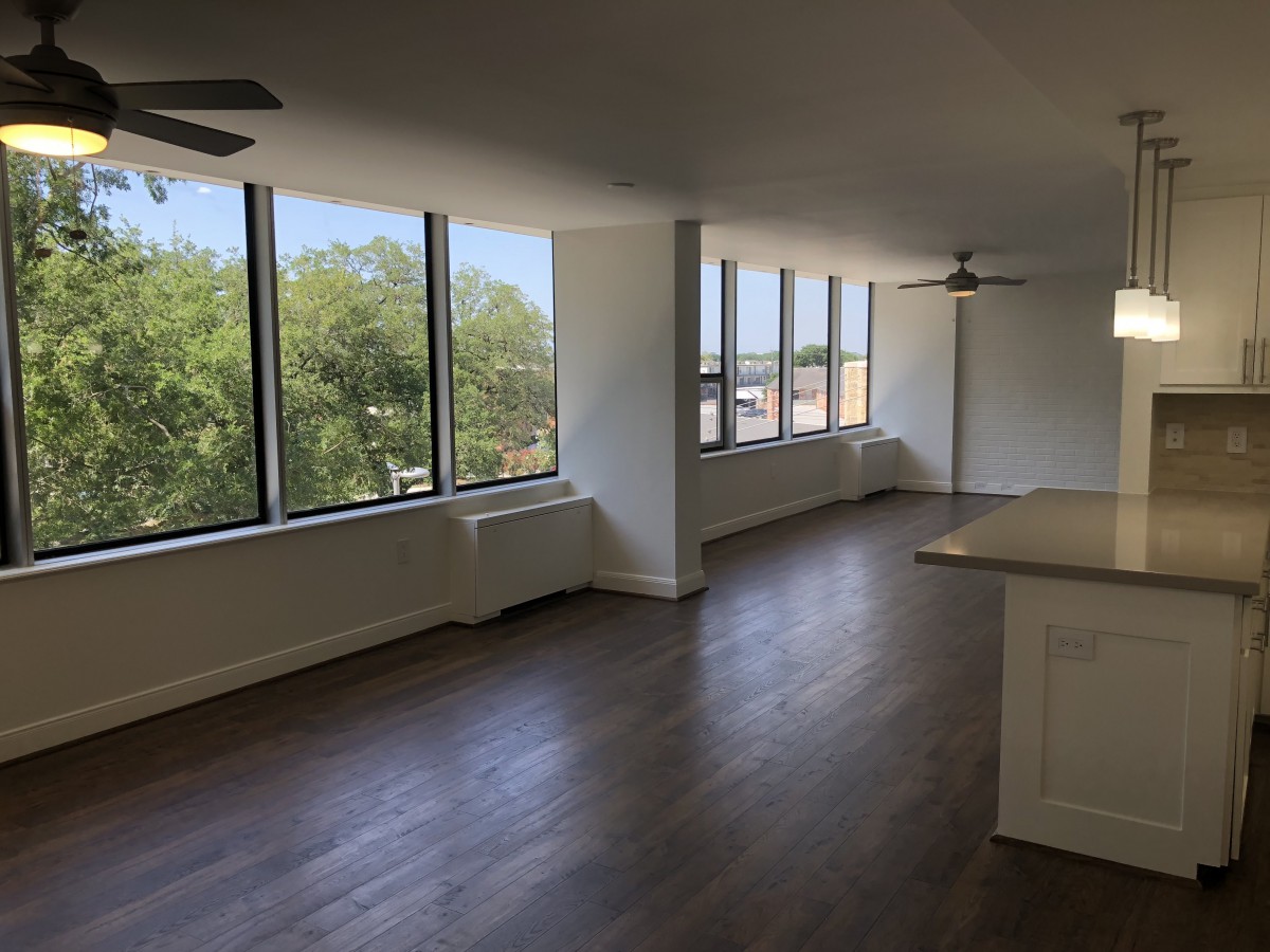 Spacious apartment with large windows and hardwood flooring, filled with natural light.