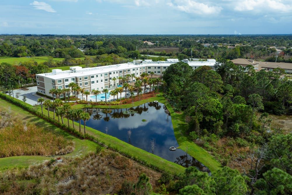 An aerial view of a hotel surrounded by lush greenery and a tranquil lake.