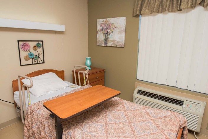 A cozy bedroom with a neatly made bed, bedside table, and wall decor.