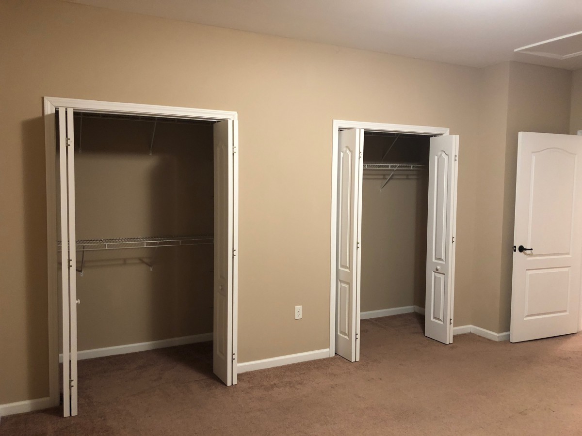 An empty room with two closets and beige walls.