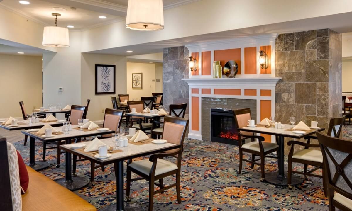 A cozy dining area with neatly set tables and a fireplace.