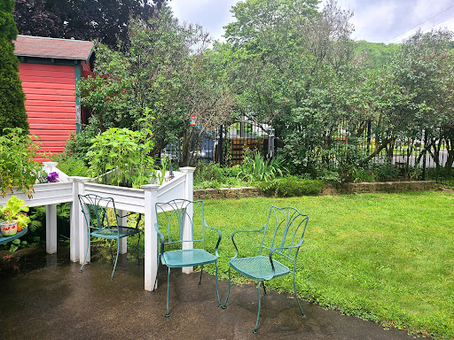 A peaceful garden scene featuring green chairs and lush vegetation, with a hint of rain.