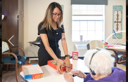A caregiver engages with an elderly individual during a recreational activity, promoting social interaction and mental stimulation.