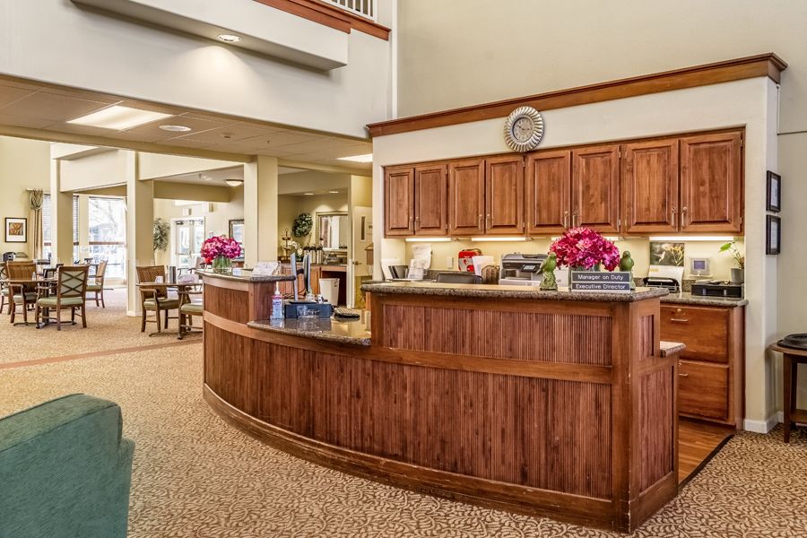 A welcoming hotel lobby with a wooden front desk and floral decor.
