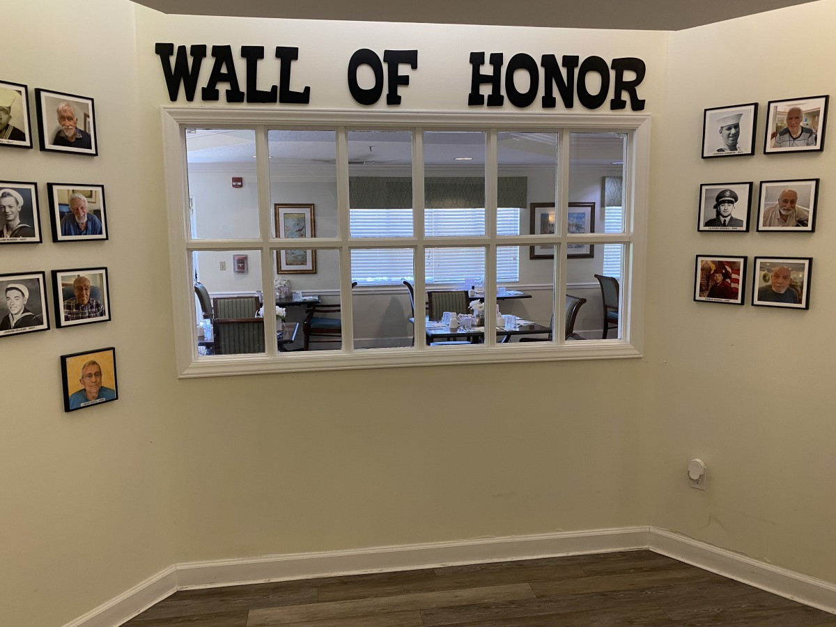 A Wall of Honor display inside a building, featuring framed pictures and recognitions.