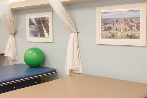 A tranquil therapy room featuring a green exercise ball, framed photographs on the wall, and a neatly arranged table.