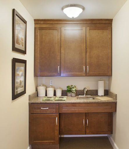A cozy bathroom vanity area featuring wooden cabinets, a sink, and decorative art.