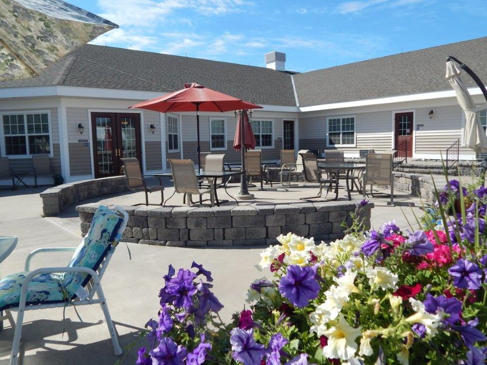 A sunny outdoor patio with tables and chairs, surrounded by colorful flowers.