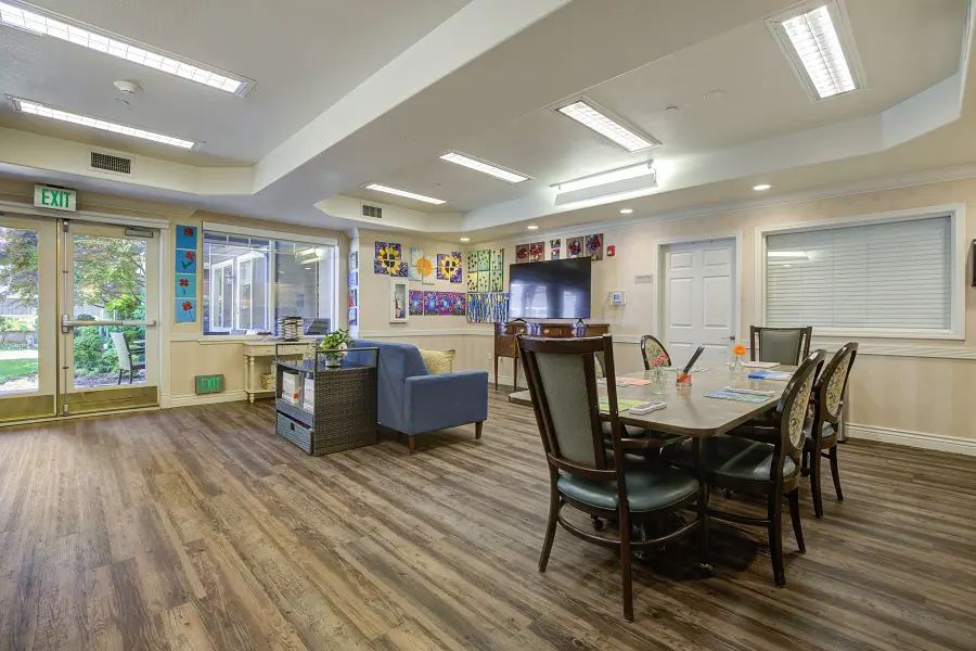 A cozy and well-lit communal living space with a dining area and seating arrangements.