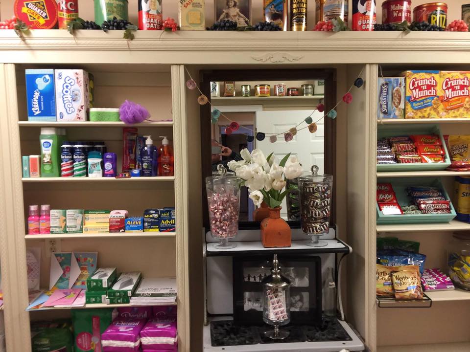 A small store display with shelves of products, including candy jars and stationery items.