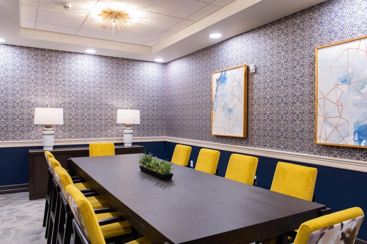 A modern conference room with yellow chairs and decorative wallpaper.
