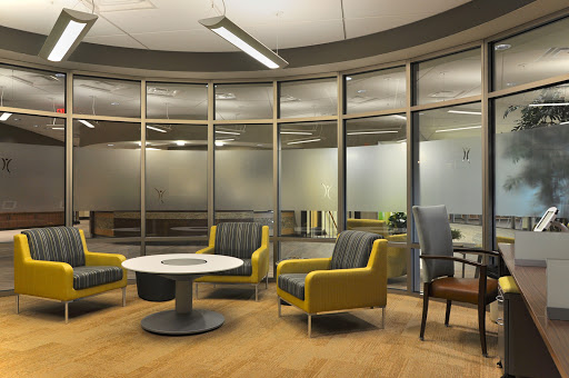 A modern office waiting area featuring contemporary furniture and glass walls.