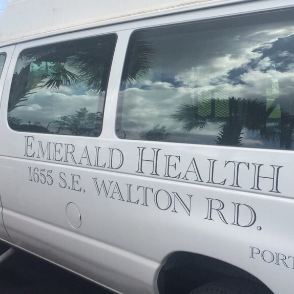 A white company van with 'Emerald Health' signage and location details on the side.