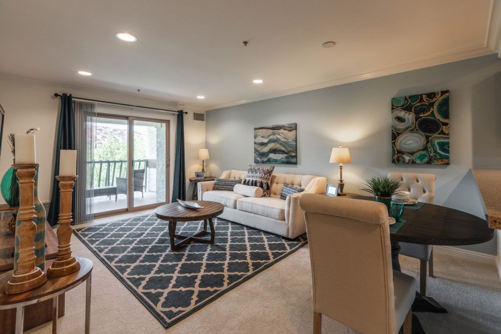 A modern and cozy living room with neutral colors, featuring a sofa, coffee table, and artwork.