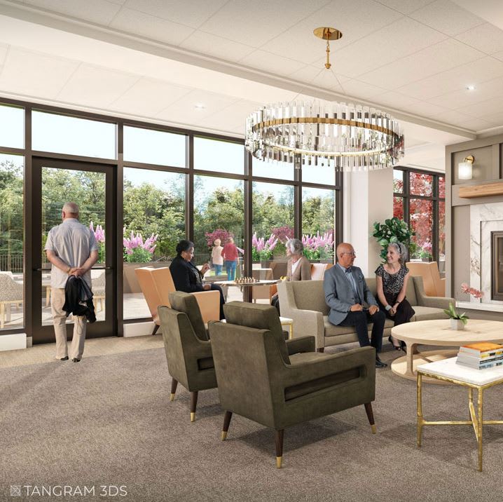 A cozy lounge area with people sitting and standing, featuring comfortable seating and a large chandelier.