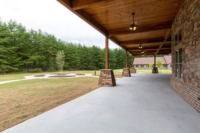 A spacious wooden-ceiling patio overlooking a lawn and wooded area.