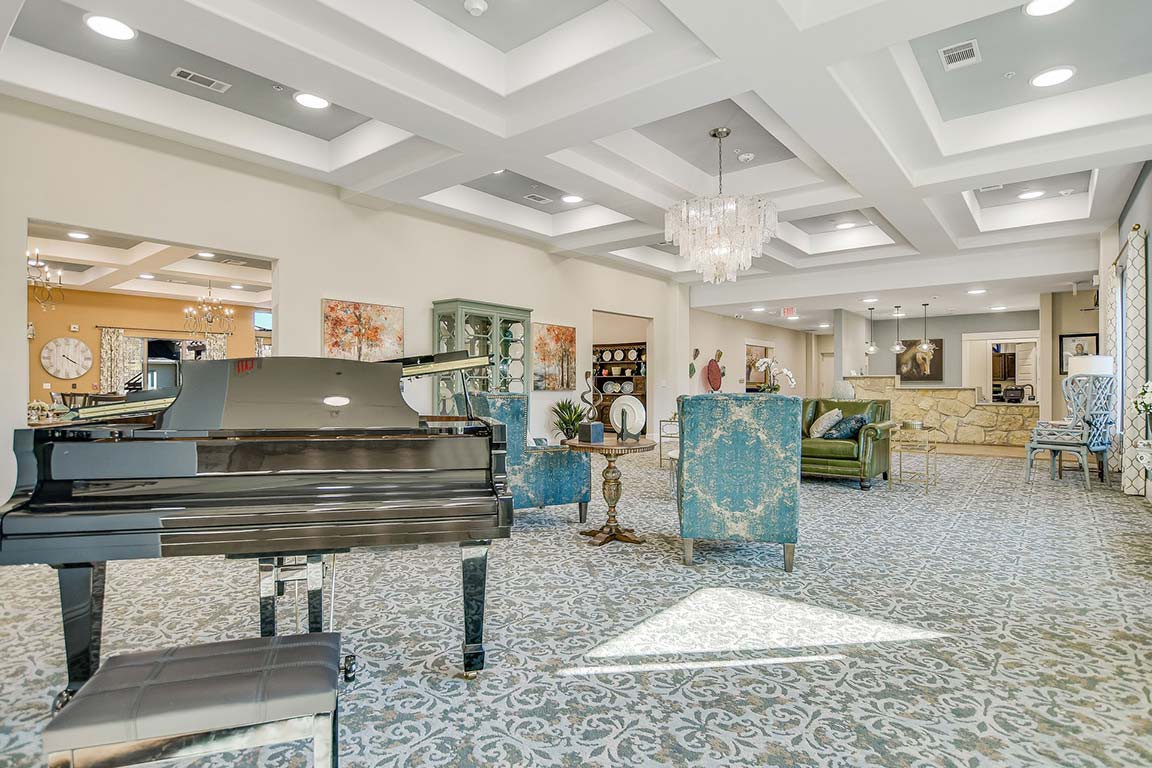 A luxurious and modern living room featuring a grand piano, elegant furniture, and stylish artwork.