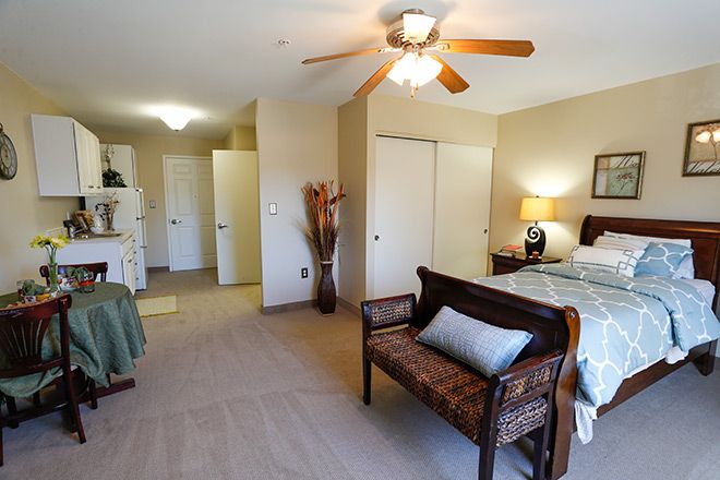 A cozy bedroom with a ceiling fan, featuring a comfortable bed and a decorative bench.